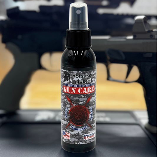 Forsaken Industries Gun Care CLP bottle on shooting mat with blurred pistol in background – veteran-owned firearm cleaner, lubricant, and protectant
