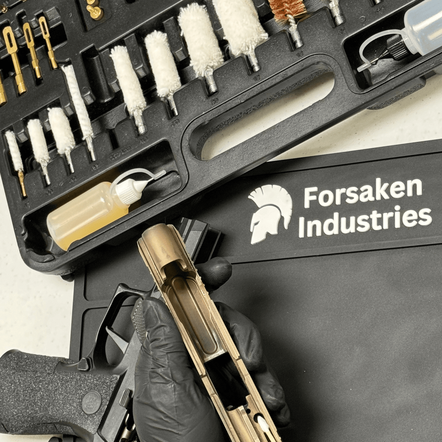Forsaken Industries Gun Cleaning Kit in use with pistol cleaning and magnetic gun cleaning mat for organized firearm maintenance